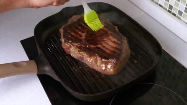 Man Hand Smoothing Oil with a Silicone Brush on Grilled Beef Steak on Grill Pan — Stock Video