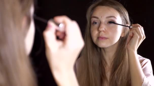 Schönes lächelndes Mädchen, das Wimperntusche aufträgt und in den Spiegel schaut — Stockvideo