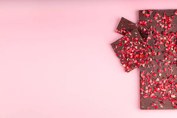 Chocolade met stukjes gedroogde aardbeien ligt een stapel op roze achtergrond — Stockfoto