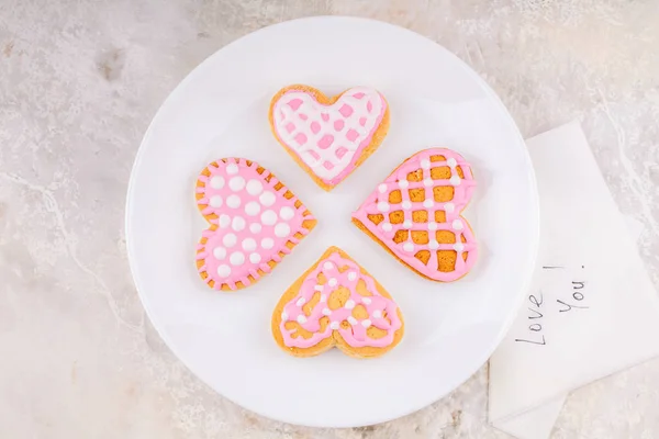 Servet met liefdesboodschap Tekst en witte plaat met handgemaakte beschilderde koekjes — Stockfoto