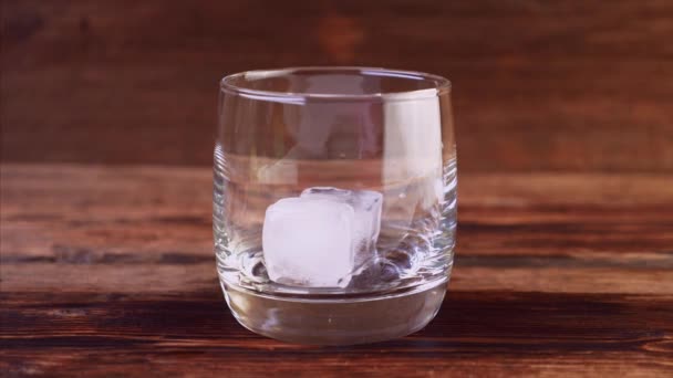 Nahaufnahme von herabfallendem Eis, das Whiskey ins Glas gießt — Stockvideo