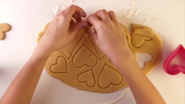 Žena ruční výroba odstraňuje nadbytečné těsto z sušenek tvarované jako srdce — Stock video