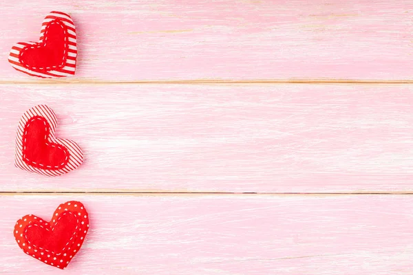 Valentijnskaarten achtergrond met handgemaakte rode naaide kussen harten in rij — Stockfoto