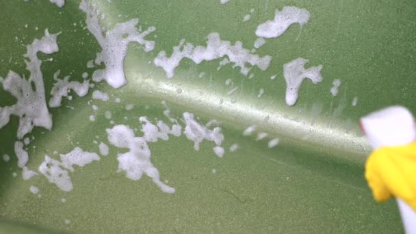 Mão em Luva Amarela Usando Espuma Branca Detergente Pulverizador Em Green Glittering Bath — Vídeo de Stock