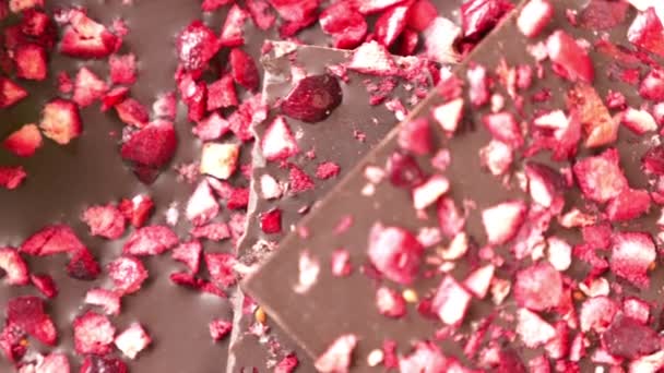 Gros plan de chocolat avec des morceaux de fraises séchées repose sur une pile — Video