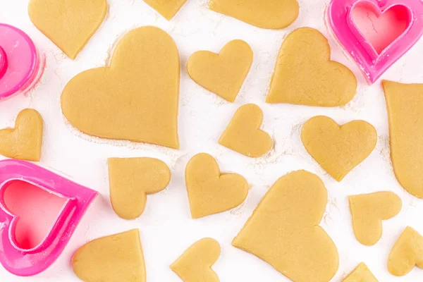 Rauwe zelfgemaakte hartvormige koekjes met roze koekjessnijder en bloem — Stockfoto