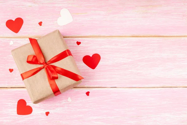 Gift Box with Red Ribbon Bow and Confetti Hearts on Pink Wooden Background — Stock Photo, Image