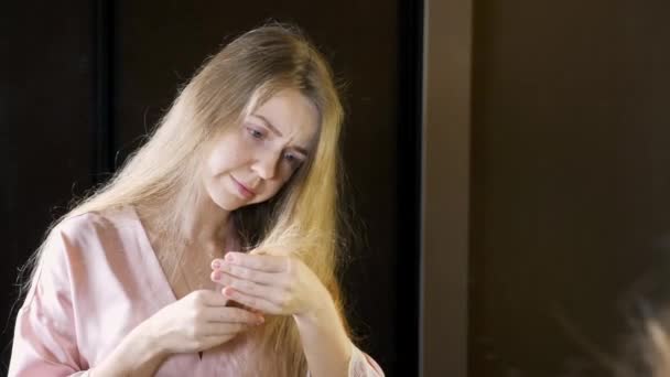 Unhappy Woman with Dry Brittle Hair Checking Her Brittle Tips in Mirror — Stock Video