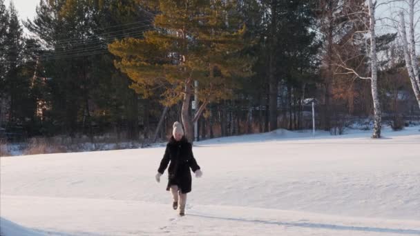 快乐的年轻女子在雪地上奔跑，在冬天的森林里玩乐 — 图库视频影像