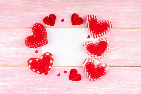Biała kartka okolicznościowa z ręcznie robionymi sercami tekstylnymi na różowym drewnianym tle — Zdjęcie stockowe