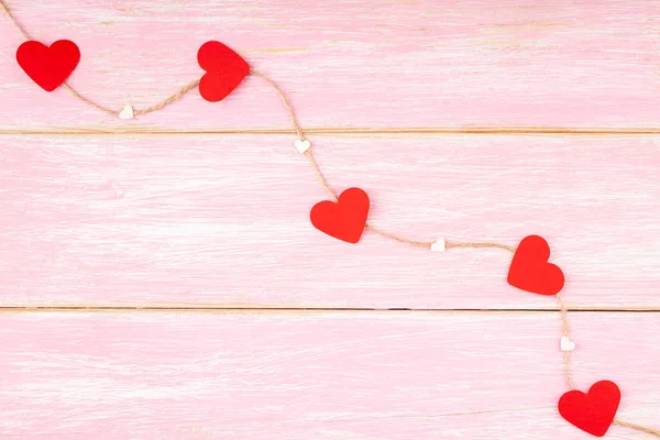 Cuerda de yute con corazones de purpurina roja y corazones de confeti sobre fondo rosa — Foto de Stock
