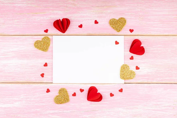 Tarjeta de felicitación blanca en blanco con corazones textiles hechos a mano sobre fondo de madera rosa — Foto de Stock