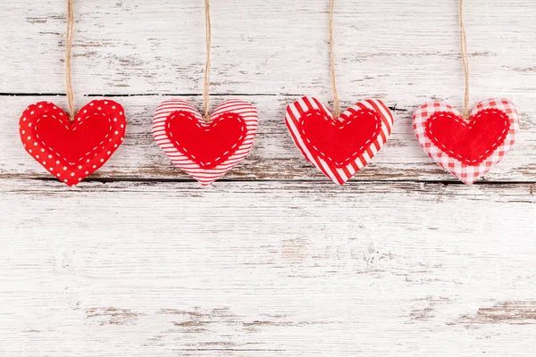 Costura corazones de almohada fila frontera de tela roja en rústico fondo de madera blanca — Foto de Stock