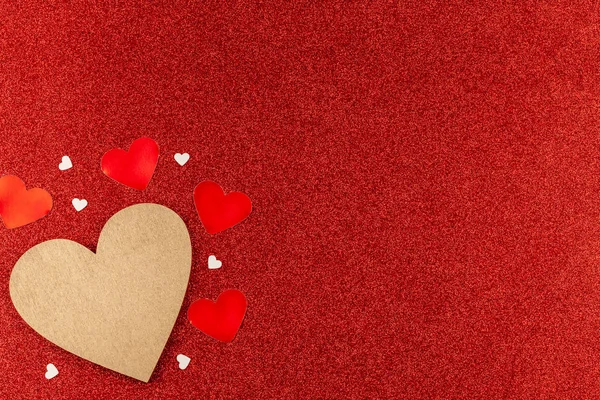 Corazón de madera dorada con pequeños corazones alrededor en fondo rojo brillo — Foto de Stock