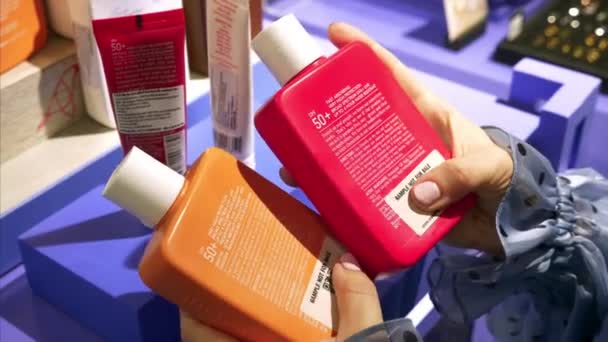 Vrouwelijke zorgvuldig analyseren en vergelijken cosmetica producten voor haar lichaam in de markt — Stockvideo