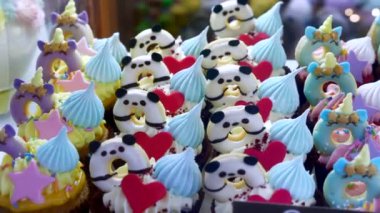 Counter with Cute Variety Cupcakes with Unicorns and Pandas on Showcase in Cafe