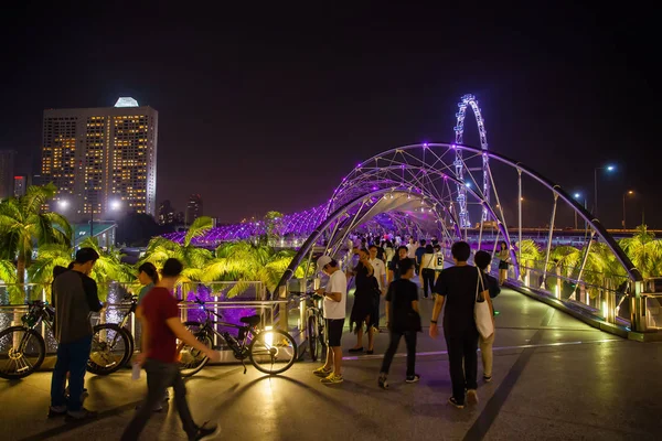 Helix Bridge e Walking People à noite com Singapore Flyer em segundo plano — Fotografia de Stock