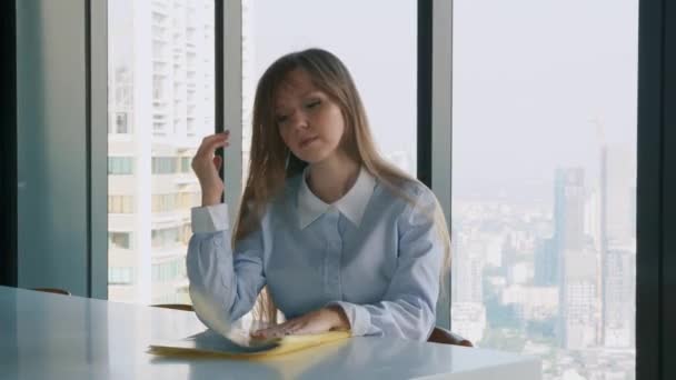 Triste mujer de negocios mirando la carpeta con documentos cerca de la ventana — Vídeos de Stock
