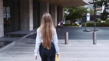 Ofis binası yakınlarında Evrakları Olan Genç İş Kadını Yürüyor