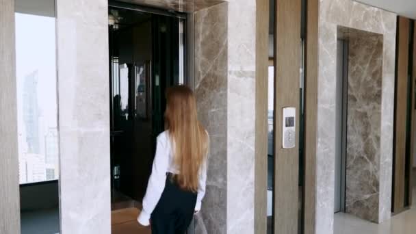 Une jeune femme d'affaires prospère marche à l'intérieur de l'ascenseur dans un immeuble de bureaux — Video