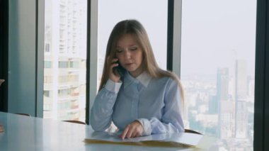 Ciddi İş Kadını Ofiste Oturuyor ve Akıllı Telefonu Müşteriyle Konuşuyor