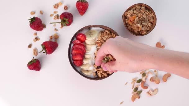 Kobieta ręka posypać orzechy w Smoothie Bowl z Granola, orzechy, świeże owoce — Wideo stockowe