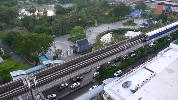 Bts de métro hors sol au-dessus de la route avec des voitures et parc tropical vert — Video