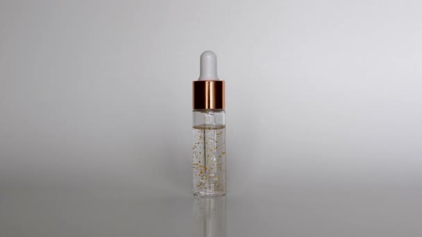 Pipette cosmétique dans une bouteille en verre transparent maquillée sur fond blanc — Video