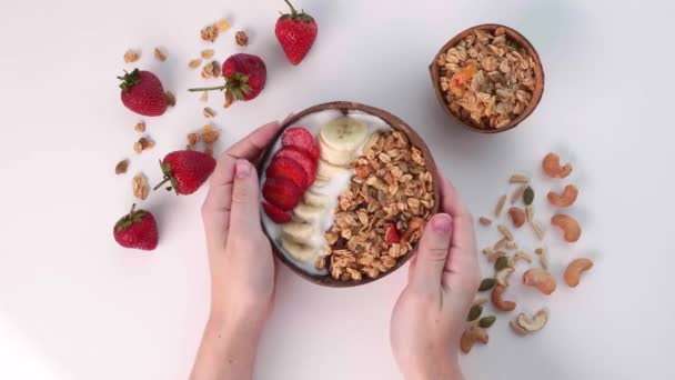 Tazón de batido vegano con Granola, frutos secos, frutas frescas y bayas en la mesa blanca — Vídeo de stock