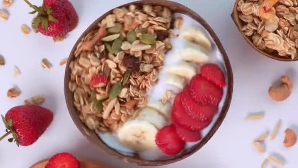 Nahaufnahme einer rotierenden Smoothie-Schüssel mit Erdbeere, Nüssen und Müsli — Stockvideo