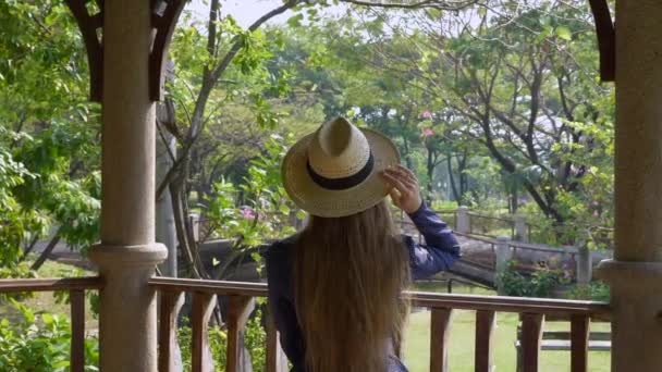 Беззаботная женщина в Соломенной Шляпе наслаждается природой в общественном летнем парке — стоковое видео