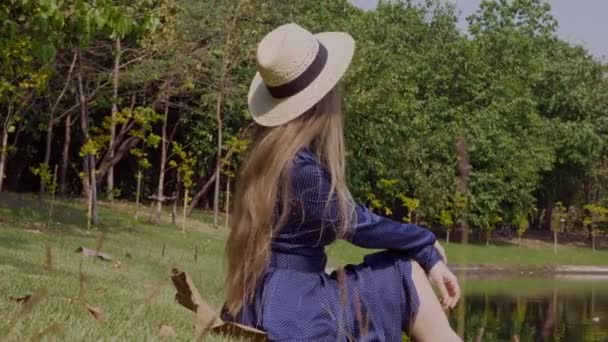 Donna Turistica con Capelli Lunghi in Cappello di Paglia Seduta e Relax vicino al Lago — Video Stock