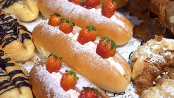 Primer plano de bollos frescos con fresa y crema en el mostrador de la pastelería — Vídeo de stock