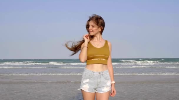 Jeune femme attrayante se tient sur le bord de la mer avec cascade de vagues sur fond — Video