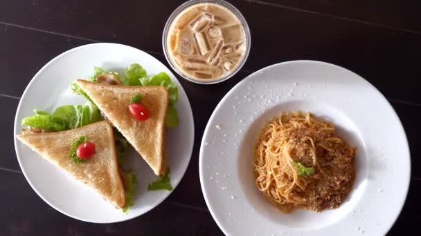 Bovenaanzicht van vers gekookte spaghetti bolognese, sandwiches en glas koffie — Stockvideo