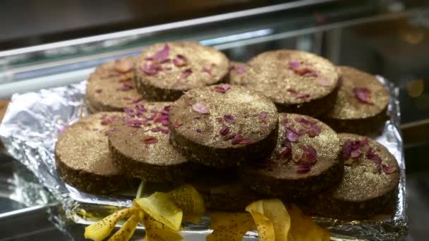 Tortas de chocolate vegano crudo con cacao, pétalos de flores y polvo de oro en Café — Vídeos de Stock