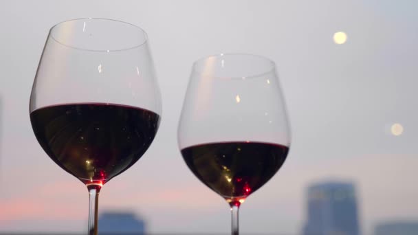 Людина бере склянку червоного вина. Два келихи перед заходом сонця ввечері — стокове відео