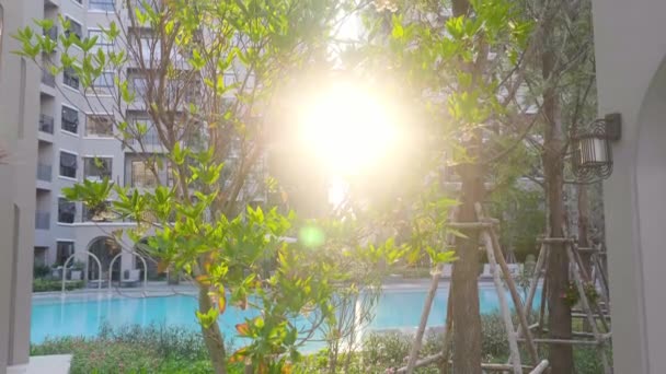 Atardecer brilla a través de la vegetación tropical cerca del complejo de condominios en Tailandia — Vídeo de stock