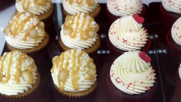 Cupcakes mit Sahnebelag und Karamell in der Vitrine der Konditorei — Stockvideo