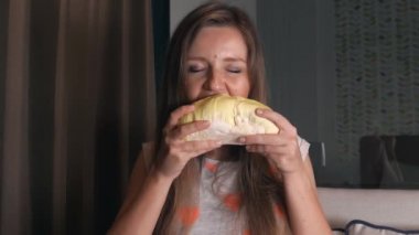 Oturan ve Zevkle Egzotik Tayland Meyveli Durian Isıran ve Yiyen Genç Kadın