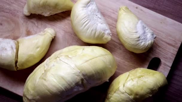 Trozos de Durian yacen en una tabla de madera. Vista superior de la fruta asiática dulce y apestosa — Vídeos de Stock