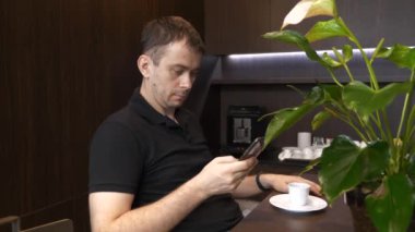 Kafede Akıllı Telefonla oturan ve İyi İnternet Haberleri okuyan Şaşkın Adam