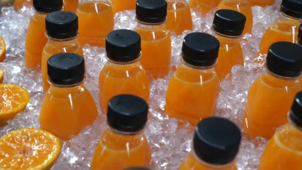Jus d'orange fraîchement pressé dans une bouteille en plastique debout dans la glace sur le marché de la rue — Video