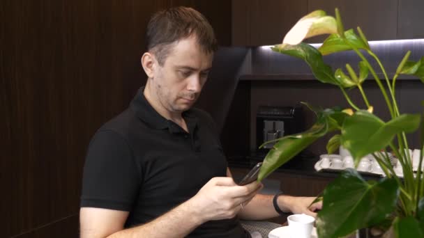 Muž s telefonem sedí v restauraci s šálkem kávy a čtení špatné zprávy — Stock video