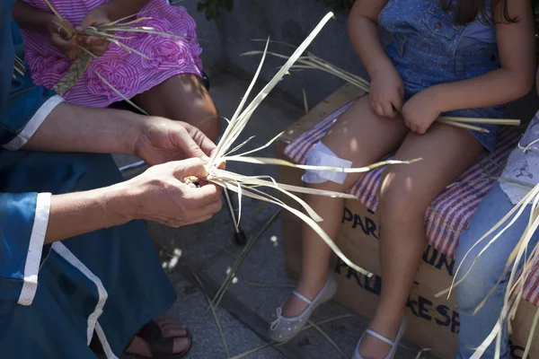 Artesãos ensinando as crianças a entrançar fibras vegetais — Fotografia de Stock