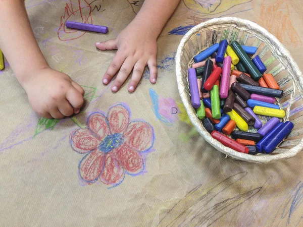 Child drawing with wax crayons over wrapping