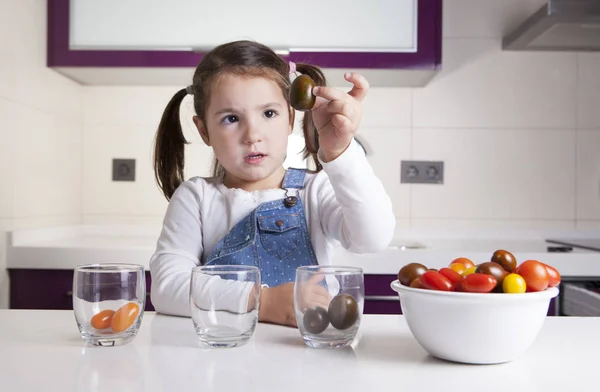 Malá holčička třídění podle barev cherry rajčátky — Stock fotografie
