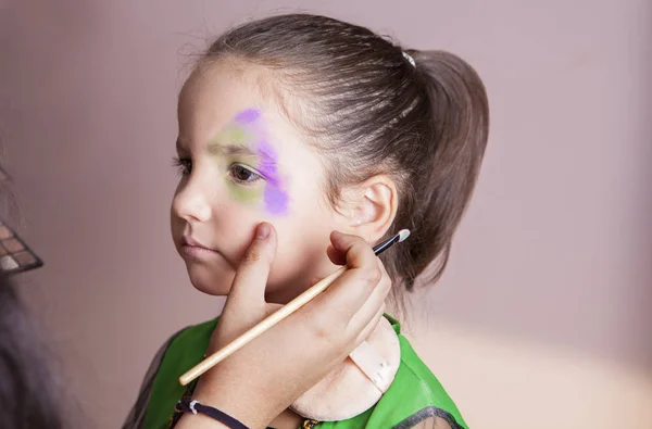Pieni söpö tyttö tekee facepaint ennen halloween puolue — kuvapankkivalokuva