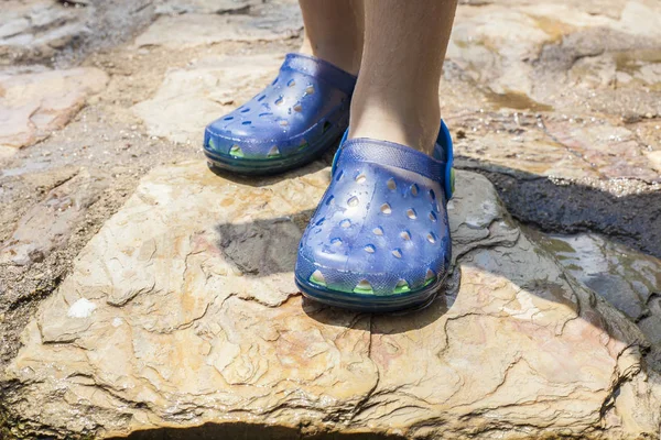 Pequena menina pernas vestindo seus tamancos de plástico azul — Fotografia de Stock