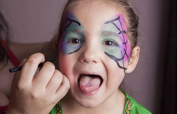Menina com a língua para fora, enquanto ela é composta por arti make-up — Fotografia de Stock